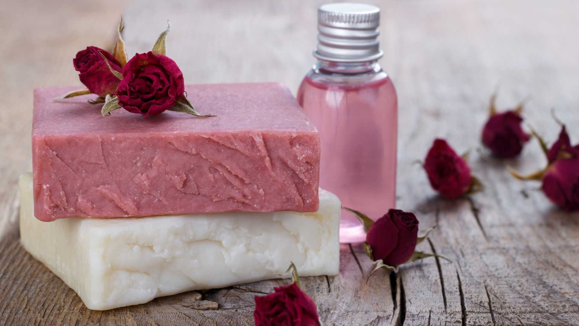 Handmade soap bars with pink roses and essential oil bottle